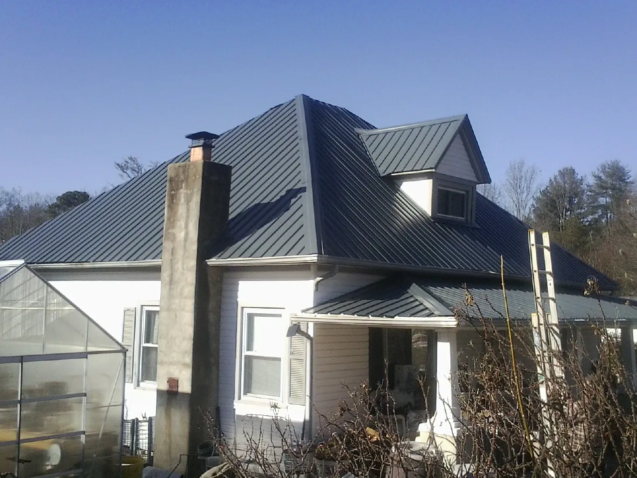 Dark blue standing seam metal roof on a white farmhouse with dormer — Slate & Tile Roof Repair by Roofing Brothers in Dover AFB