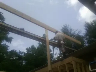 Carpenter setting a ridge beam over a new addition frame — Ice Dam Removal by Roofing Brothers in Dover AFB