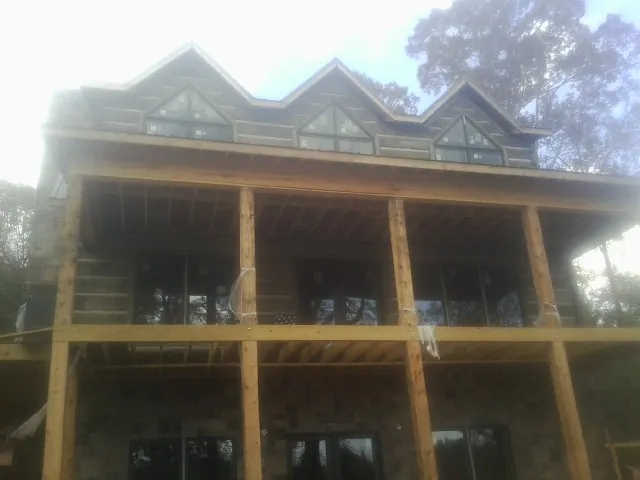 Dormers and porch framing on a large log home under construction — Roof Coating work by our crew in Dover AFB