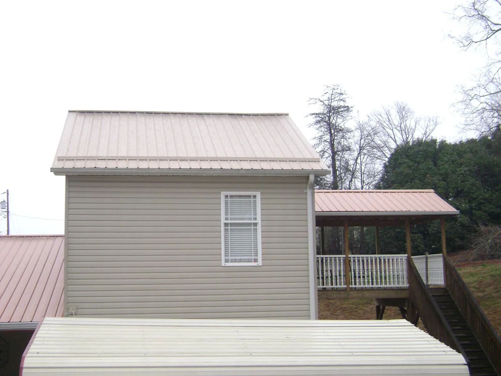 Tan metal roofs on a two story addition and attached porch, from a Roof Replacement job in Dover AFB