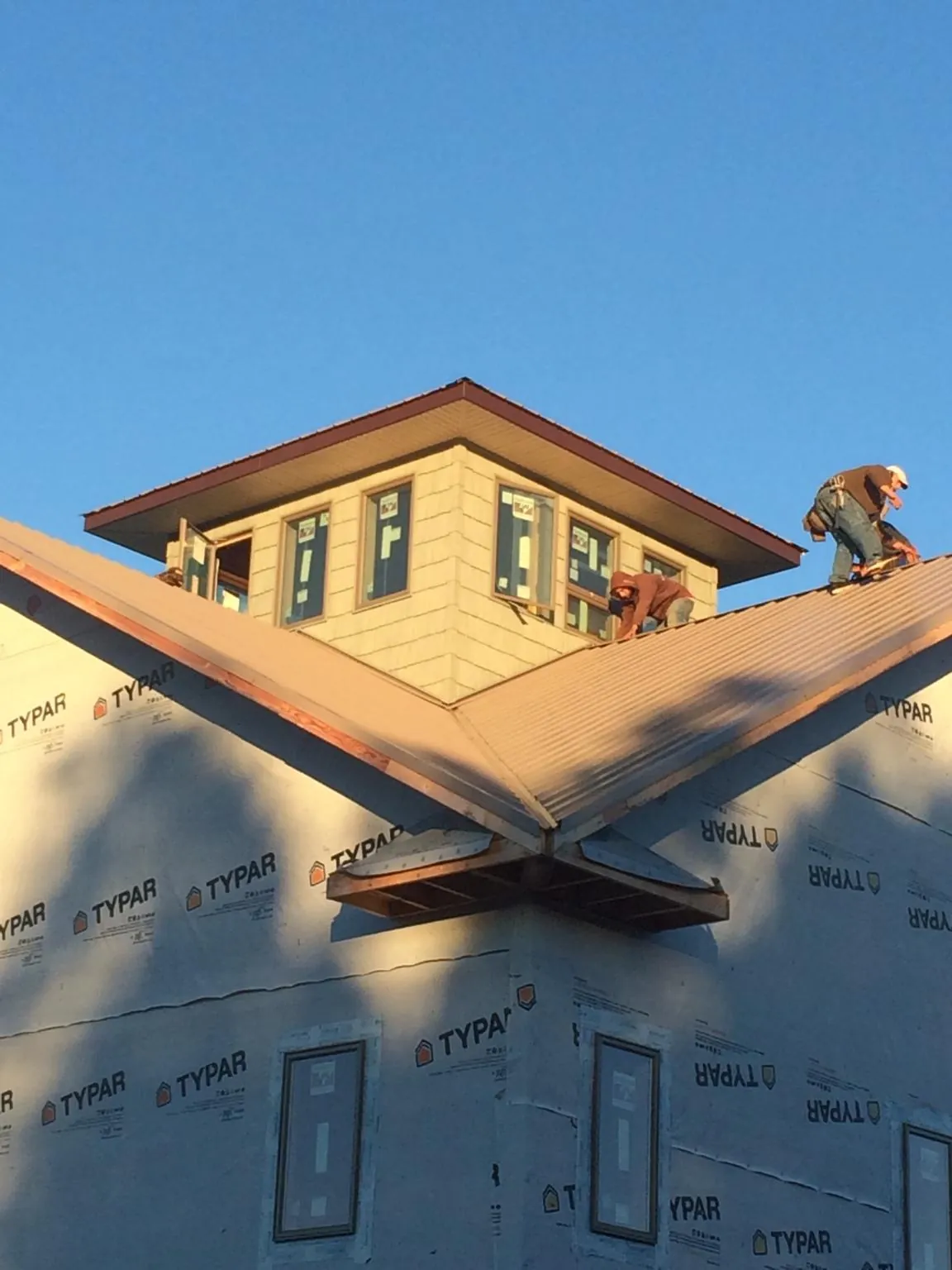 Roofers working around a rooftop cupola on a new metal roof at sunset — Roof Waterproofing in Dover AFB by Roofing Brothers